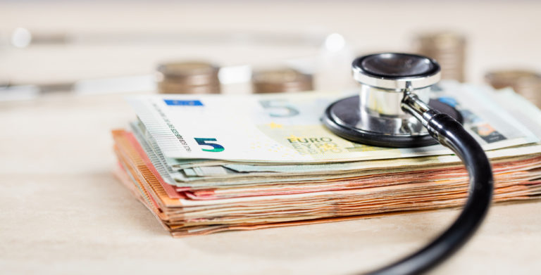 Várias notas e moedas com um estetoscópio em cima