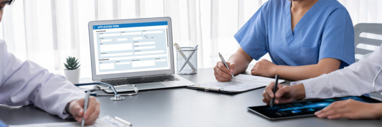 Três médicos em uma mesa assinando um documento digital